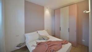 Une chambre à coucher avec un lit, une table de chevet, un magazine et une armoire.