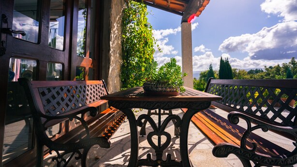 An outdoor patio with a wooden table and two benches, surrounded by stone walls and potted plants. - Douro Valley - Country house with private pool. (Marco de Canaveses)