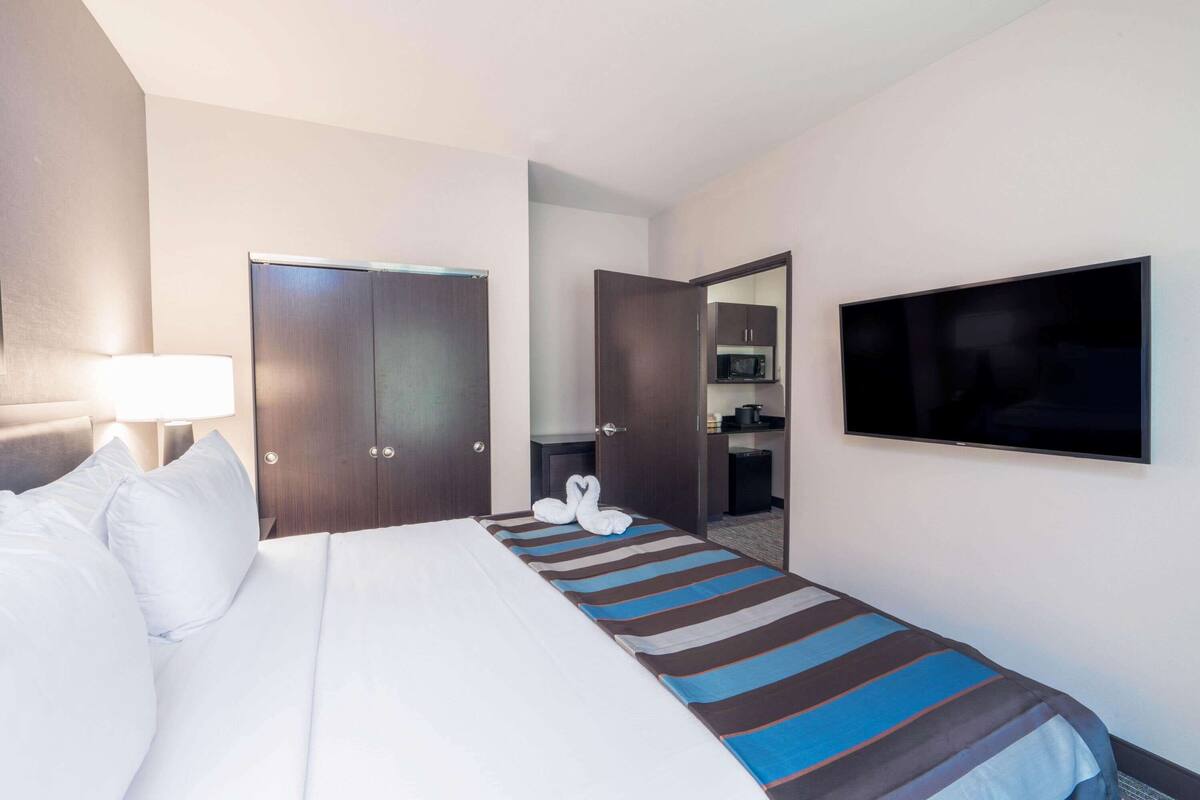 Ein Hotelzimmer mit Bett, Fernseher, Schreibtisch mit Stuhl und Kleiderschrank.