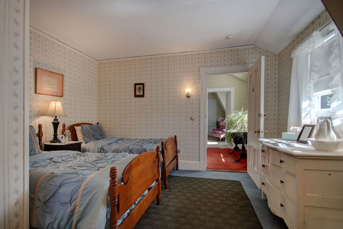A bedroom with two wooden beds, a nightstand, a dresser, and a mirror.