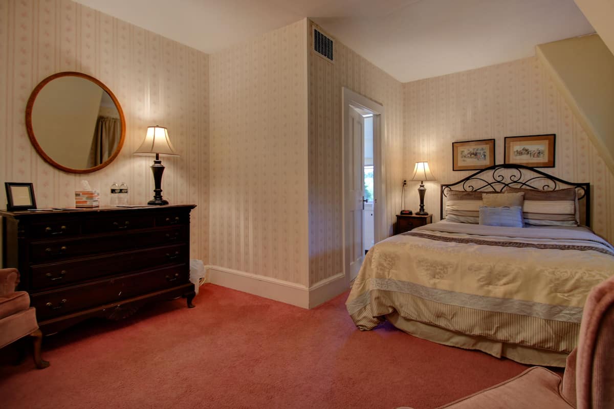A bedroom with a bed, dresser, mirror, and two bedside lamps.
