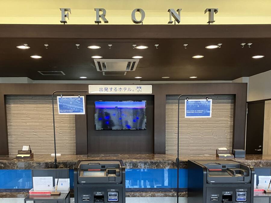 A reception area with a 'FRONT' sign, a television screen, and ATMs.
