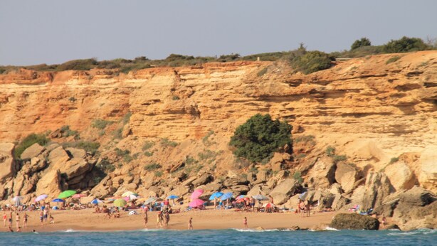 A beach with people, umbrellas, and rocky cliffs. - Holiday apartment with shared pool (CONIL DE LA FRONTERA)