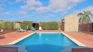 A rectangular swimming pool with a stone wall on one side and a brick patio surrounding it. - Holiday apartment with shared pool (CONIL DE LA FRONTERA)