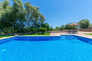 Ein Pool mit klarem, blauem Wasser, umgeben von einer Steinsäule und üppiger Bepflanzung.