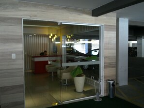 A modern interior with a glass partition, a reception desk, and a potted plant.