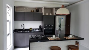 A modern kitchen with a central island, built-in appliances, and a pendant light. - Style and Comfort - Loft in Alto - Teresópolis - Wifi (Teresópolis)
