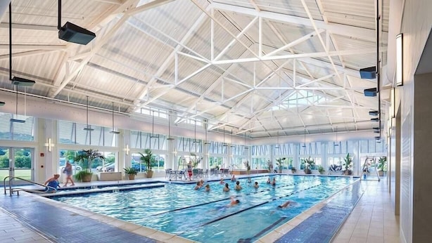 En indendørs swimmingpool med højt til loftet og store vinduer.