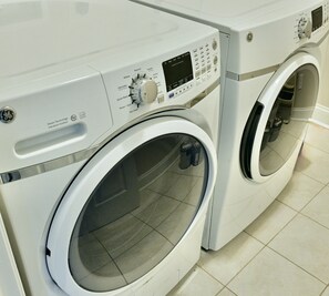 A front view of a front-loading washing machine with a control panel, a door, and a transparent door.