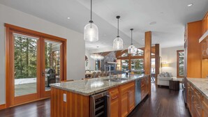 A spacious kitchen with wooden cabinets, a granite countertop, and pendant lighting. - Luxury chalet w/ hot tub & media (Whistler)