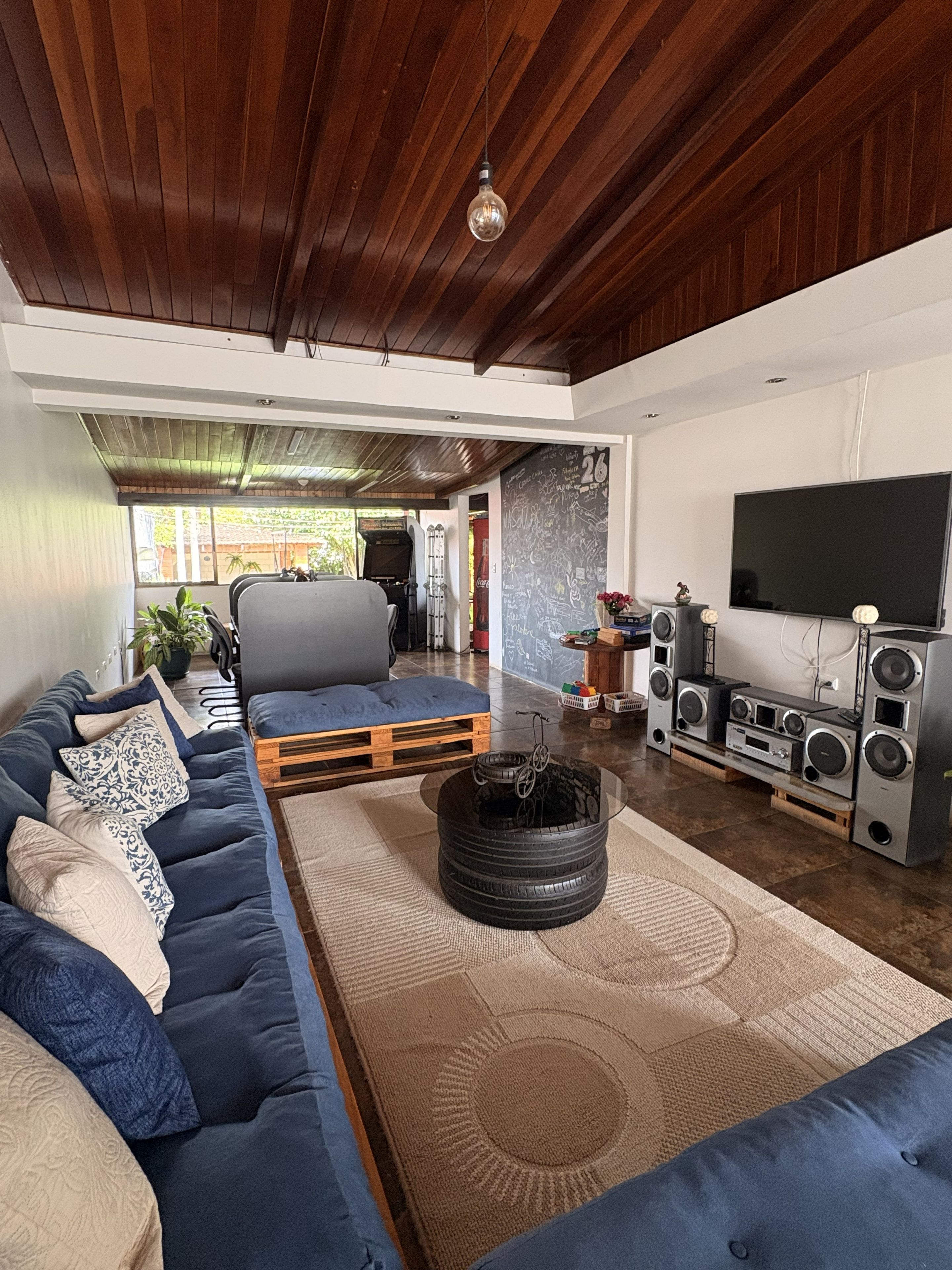Una sala de estar moderna con un sofá modular, una mesa de centro con neumáticos, un televisor y un equipo de sonido.