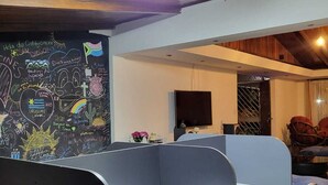 A modern office space with cubicles, a large chalkboard with colorful drawings, and a wooden ceiling. - Eco Stay CR (San José)