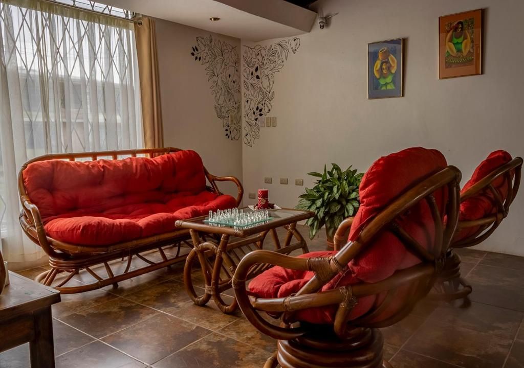 Ein Wohnzimmer mit einem roten Sofa, einem Holztisch und einer Zimmerpflanze.