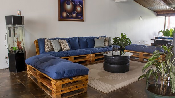 A modern living room with a blue sofa set, a wooden coffee table, and a fish tank. - Eco Stay CR (San José)