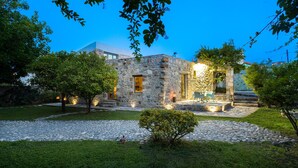 A stone building with a stone pathway leading to a seating area with chairs and a table. - Muazzo Creta Stone House, Nature Escape with Pool (Rethymno)