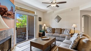 A living room with a fireplace, a ceiling fan, a sofa, and a coffee table. - Relax Poolside in your private, Clean, Beautiful, Quiet Vacation Condo (Phoenix)