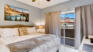 A bedroom with a bed, a ceiling fan, a window with curtains, and a view of buildings outside. - Relax Poolside in your private, Clean, Beautiful, Quiet Vacation Condo (Phoenix)