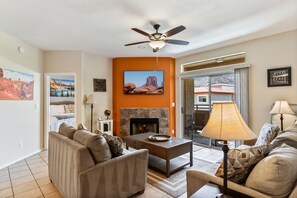 A living room with a fireplace, sofas, a coffee table, and a ceiling fan. - Relax Poolside in your private, Clean, Beautiful, Quiet Vacation Condo (Phoenix)