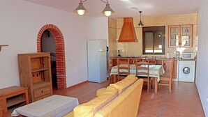 Ein kompakter Wohnbereich mit Sofa, Esstisch und Küchenzeile, inklusive Waschmaschine.