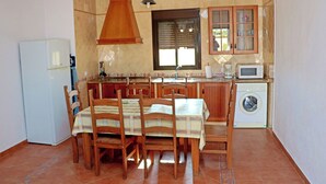 Eine kleine Küche mit Essbereich, ausgestattet mit einem Kühlschrank, Holzschränken, einer Mikrowelle und einer Waschmaschine.