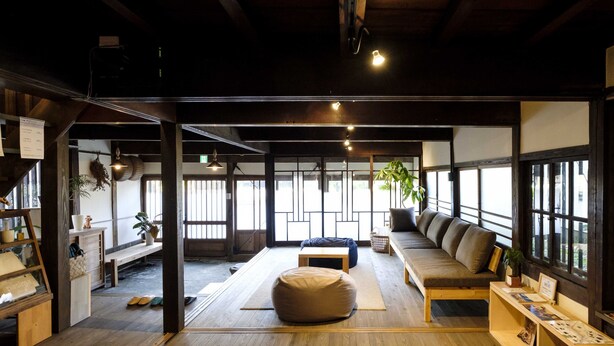 A spacious room with a wooden floor, a sofa, a bean bag, and a small table. - Guest House Maru ‐Hostel (Kashima)