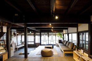 Une pièce spacieuse avec un plancher en bois, un canapé, un fauteuil poire et une petite table.