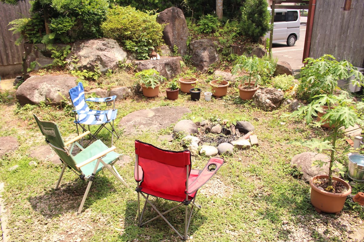 A garden with potted plants, rocks, and two folding chairs.