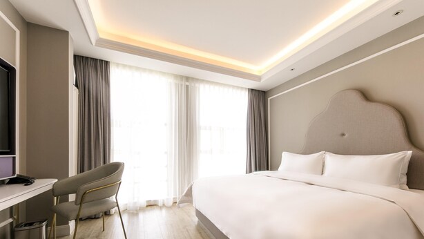 A modern hotel room with a large bed, a desk with a chair, and a television. - Mercure Ordos Downtown (Ordos)