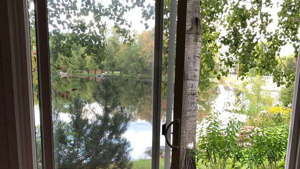Une chambre avec un lit, une vue sur un lac et une terrasse en bois à l’extérieur.
