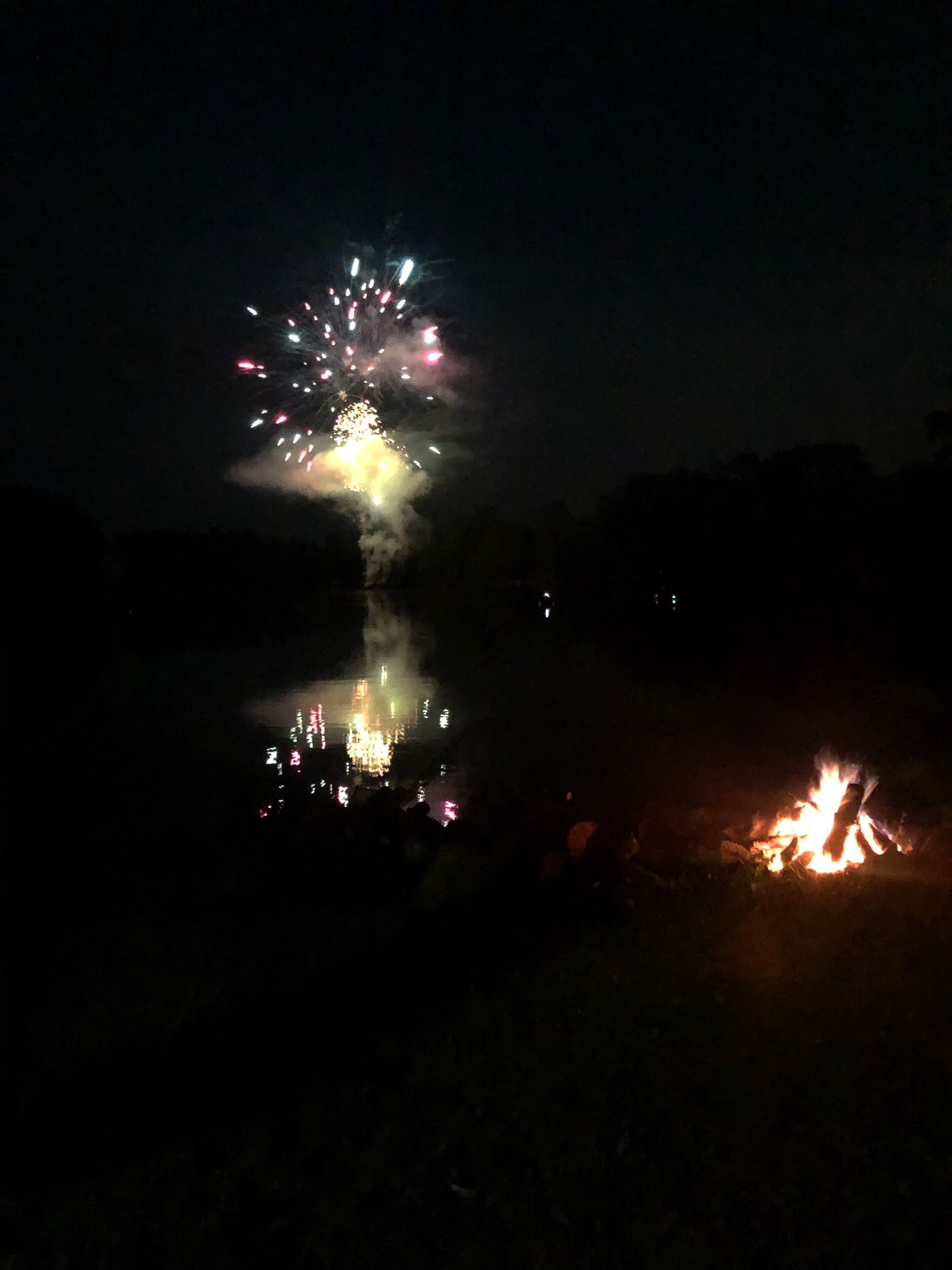 A nighttime scene with fireworks and a campfire.