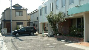 Un estacionamiento con una camioneta negra estacionada frente a un edificio con toldo verde.