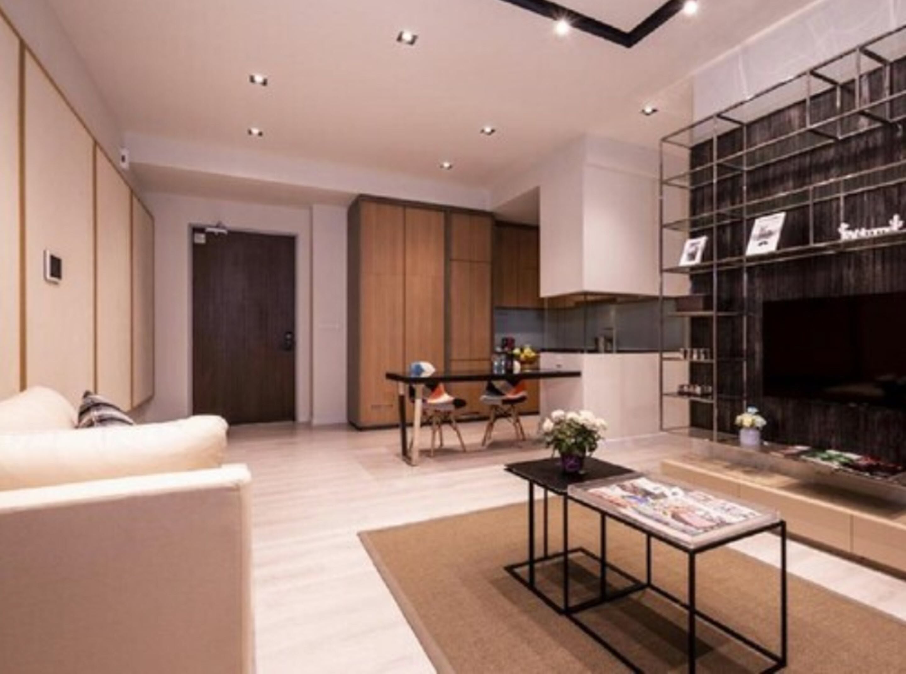 A modern living room with a sofa, a coffee table, and a kitchen area with wooden cabinets and a dining table.