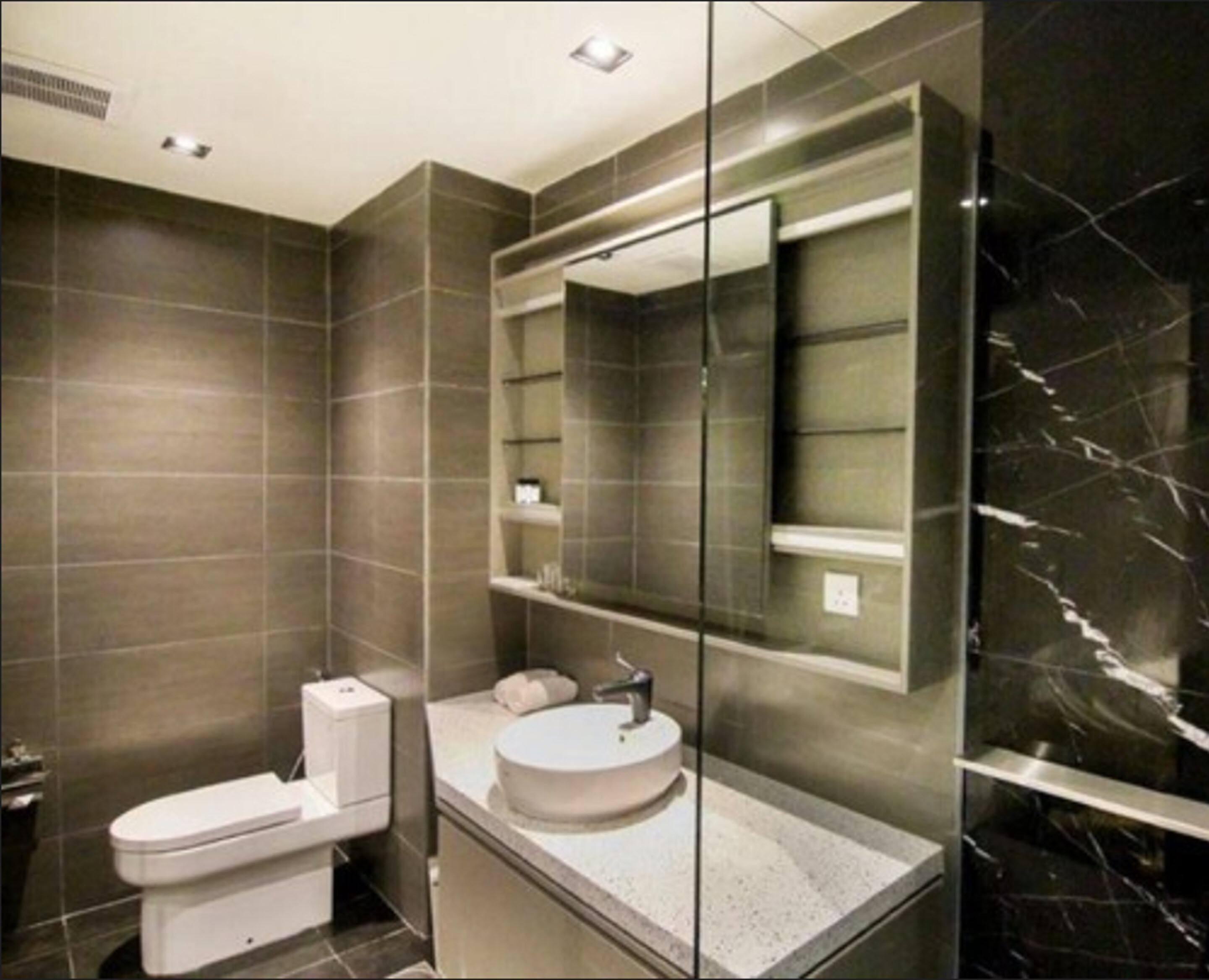 Une salle de bain moderne avec des toilettes, un lavabo et un miroir.