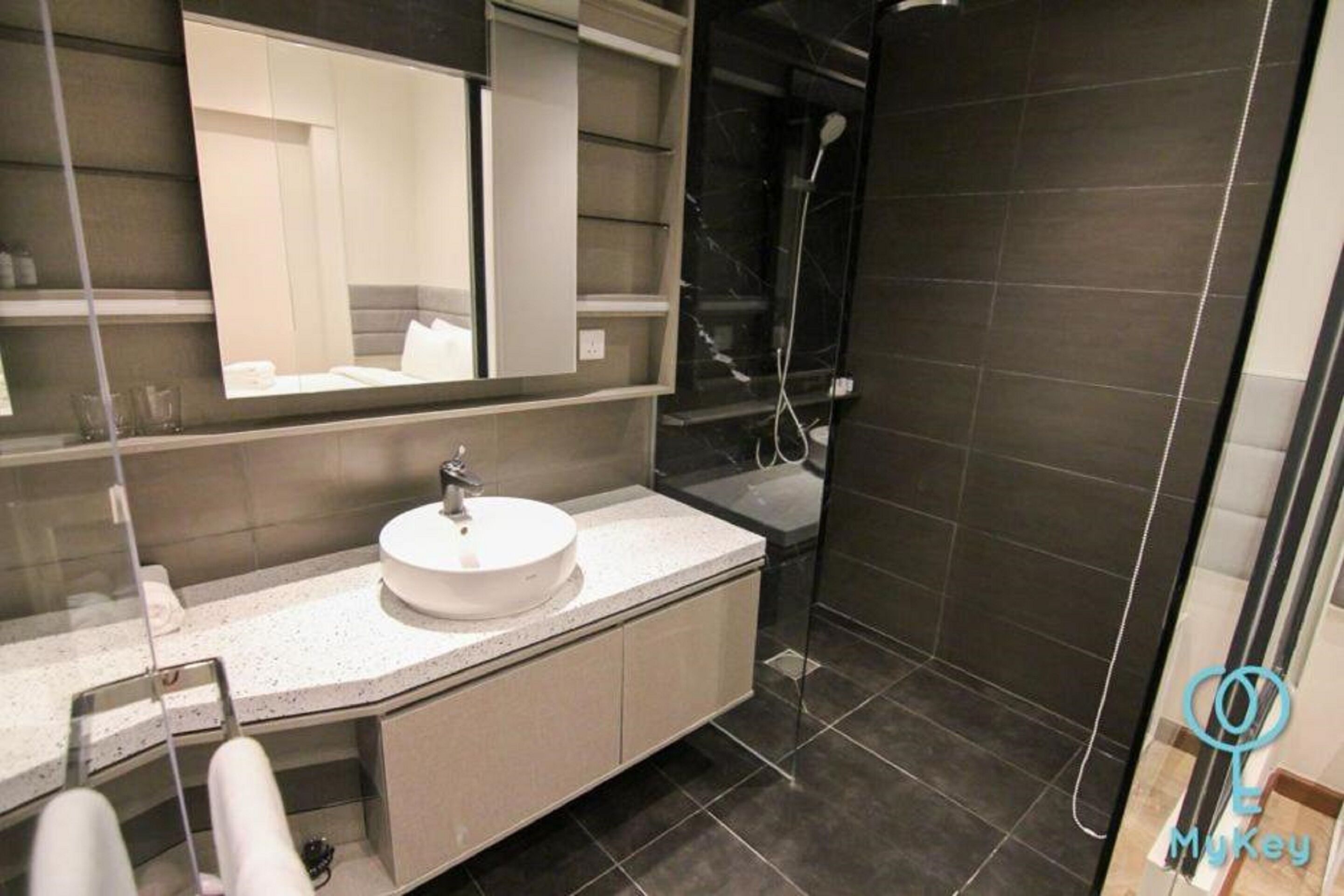 A modern bathroom with a round sink, a large mirror, and a shower area.