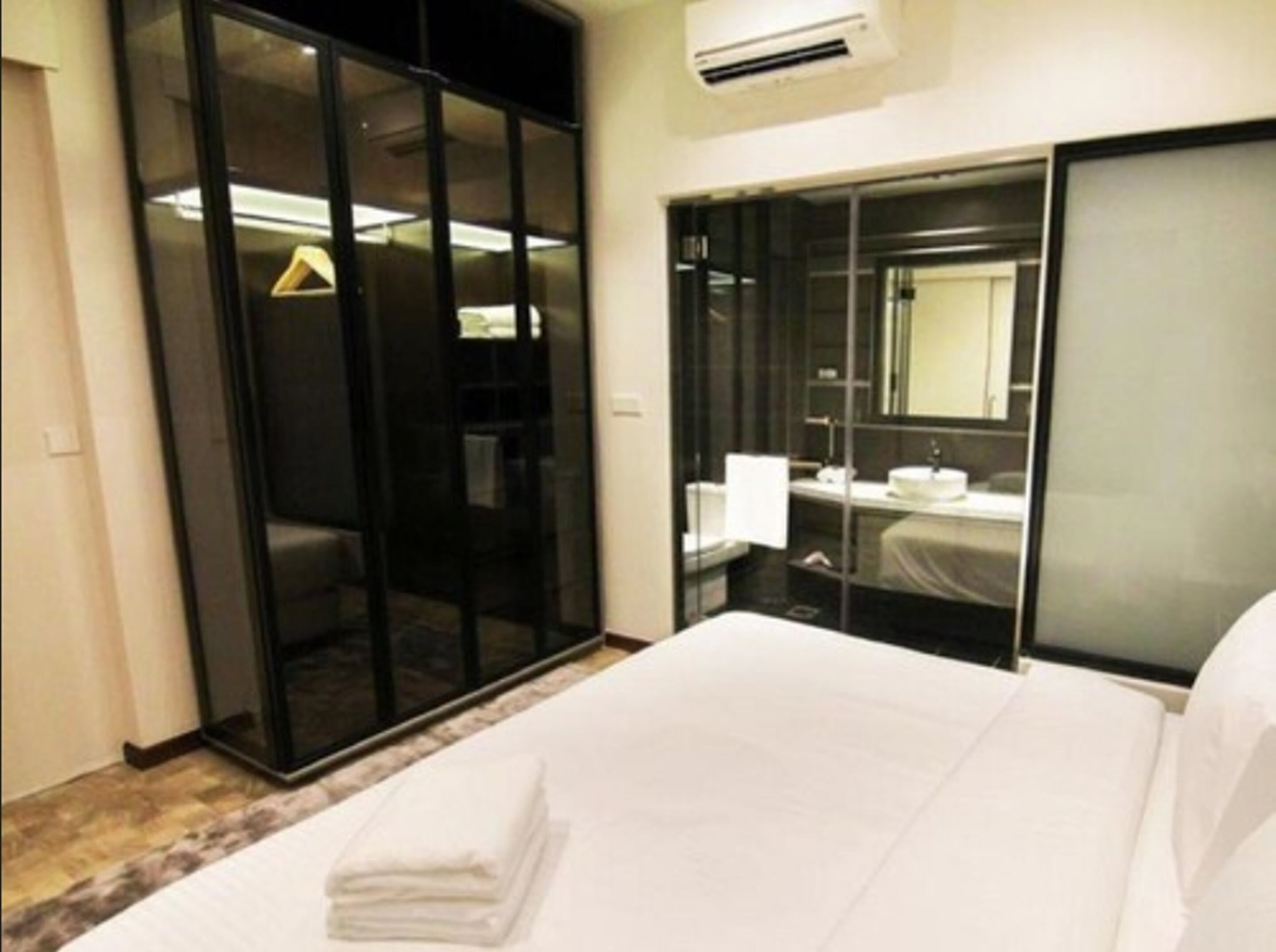 A hotel room with a bed, a bathroom with a mirror, and a wardrobe.