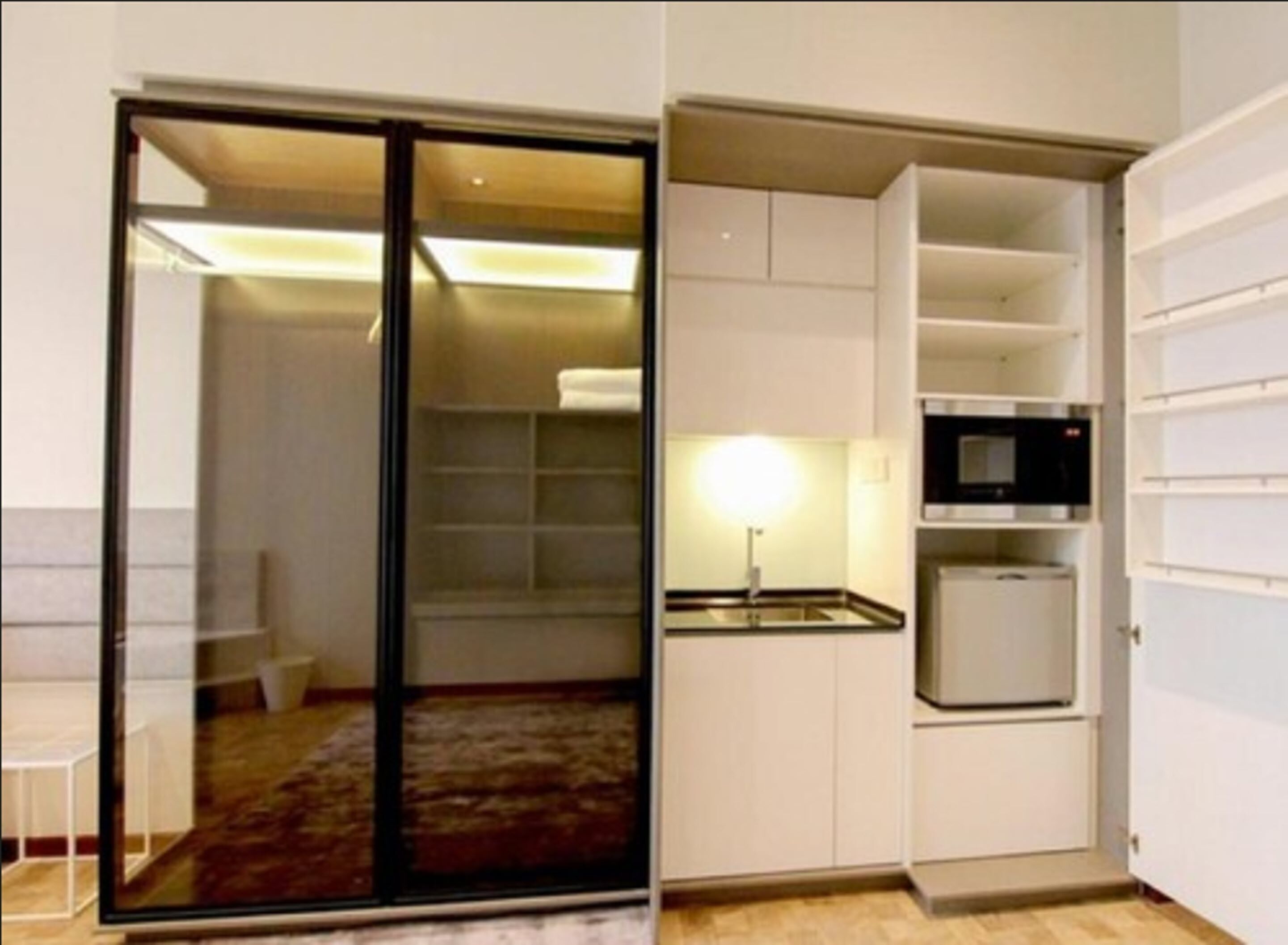 A compact kitchen with a microwave, a small refrigerator, and a cabinet with shelves.