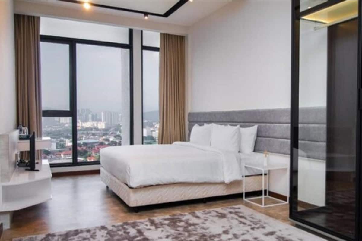 A modern bedroom with a large window, a bed, a bedside table, and a view of the city.