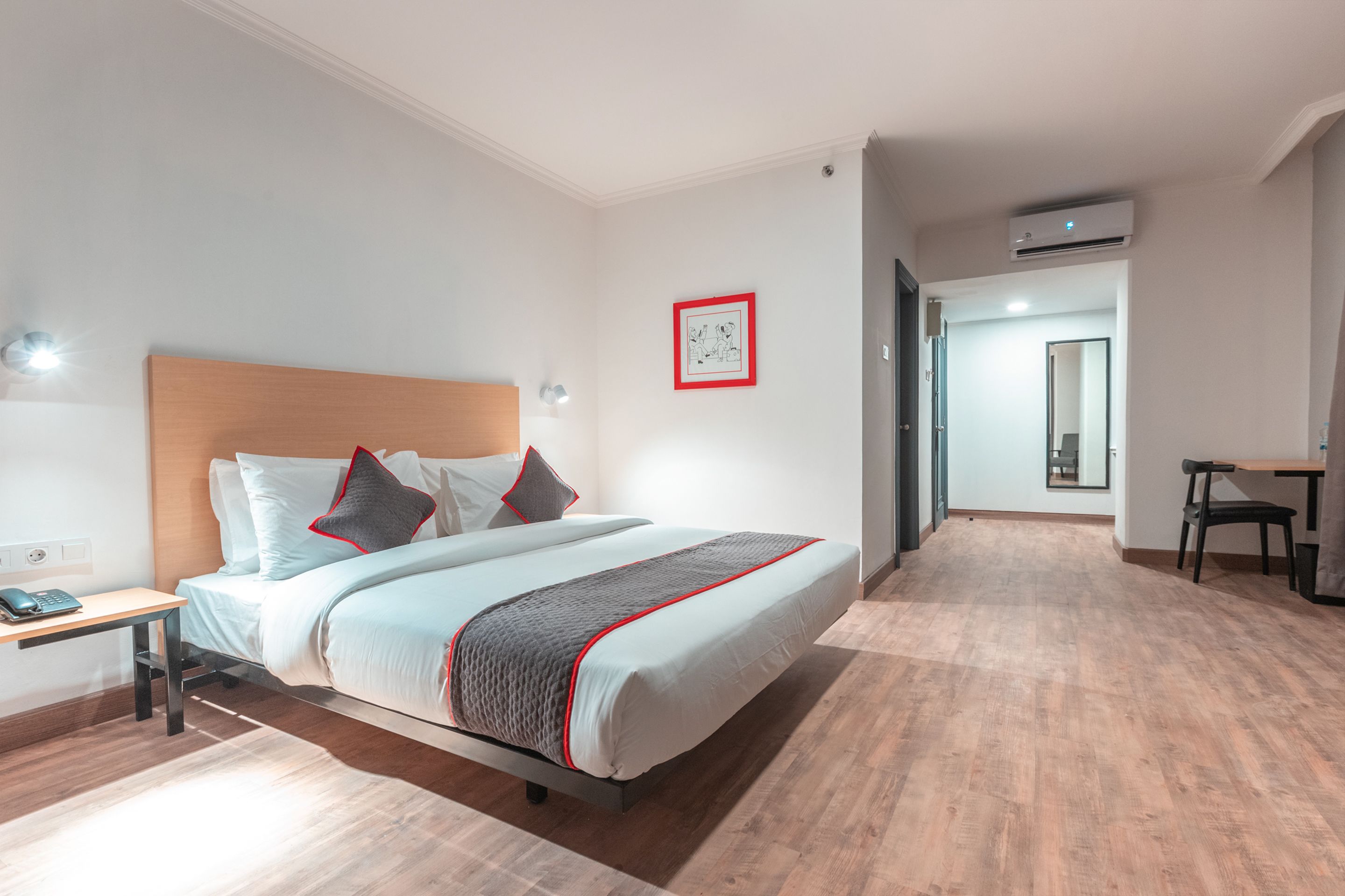 Una habitación de hotel moderna con una cama grande, una mesita de noche y un escritorio con silla.