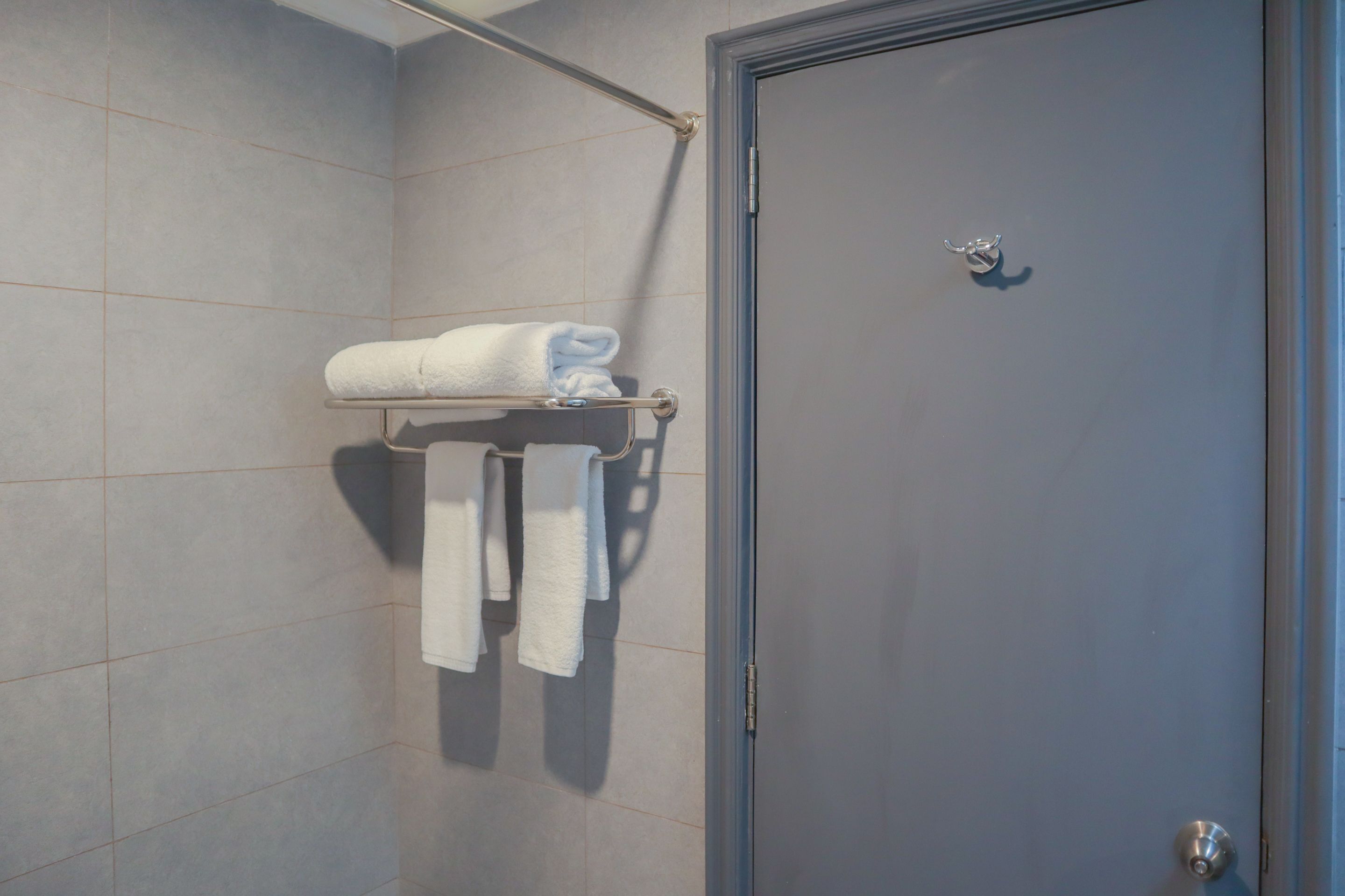 Een badkamer met een handdoekhouder met twee handdoeken en een deur met een handvat.