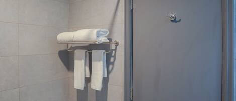 Baño con un perchero que sostiene dos toallas y una puerta con manija.