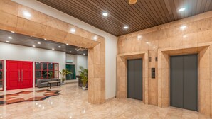 A spacious lobby with a polished marble floor, a red reception desk, and two elevators. - Super OYO Townhouse 2 Hotel Gunung Sahari (Jakarta)