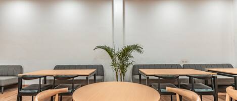 Una sala de reuniones moderna con una mesa redonda, mesas rectangulares y sofás grises.