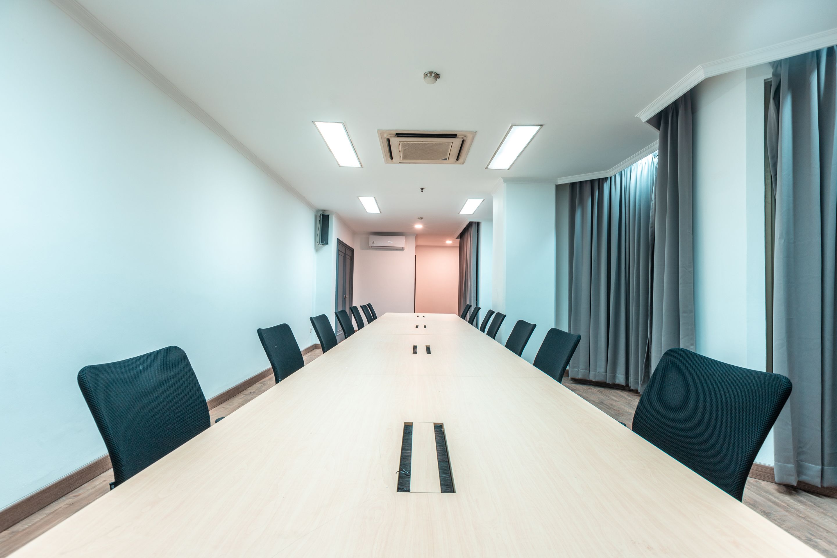 A conference room with a long table, chairs, and ceiling lights.