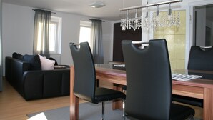 A modern living room with a sofa, two black chairs, a wooden dining table, and a chandelier. - Apartment Anita Fischbach near Dahn (Fischbach bei Dahn)
