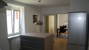 A modern kitchen with a built-in island, a refrigerator, and a dining area visible through an open door. - Apartment Anita Fischbach near Dahn (Fischbach bei Dahn)