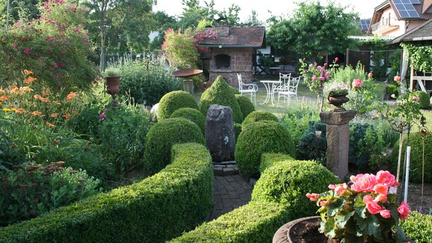 A garden with a stone bench, a potted plant, and a brick oven. - Apartment Anita Fischbach near Dahn (Fischbach bei Dahn)