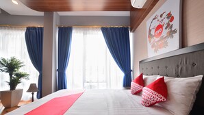 Ein Hotelzimmer mit einem großen Bett, blauen Vorhängen, einer Topfpflanze und einem an der Wand hängenden Kunstwerk.