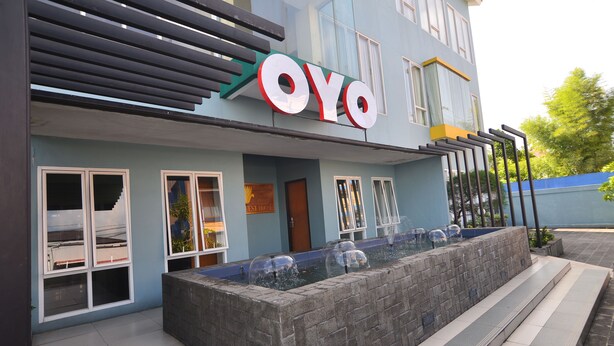 Ein Gebäude mit einem Schild mit der Aufschrift 'OYO' und einem Wasserspiel vor der Fassade.
