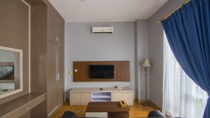 Ein modernes Wohnzimmer mit flachbildfernseher an der Wand, einem Sofa, einem Couchtisch und einem Schrank.