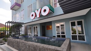 Ein Gebäude mit einer großen Beschilderung mit dem Schriftzug „OYO“ und einer Wasseranlage davor.